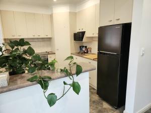 a kitchen with a black refrigerator and a plant at Holiday Haus Hahndorf - 4BR, Garden and Parking in Hahndorf