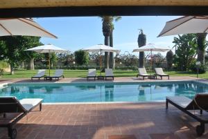 una piscina con sillas y sombrillas en Villa Carlotta Resort, en San Leone