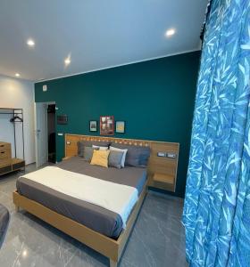 1 dormitorio con cama y pared azul en Aurora Luxury Rooms Affittacamere, en Nápoles