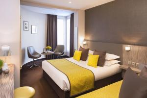 a hotel room with a large bed with yellow pillows at Acropole in Paris