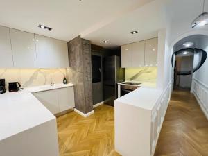kuchnia z białymi szafkami i drewnianą podłogą w obiekcie Redstripes Apartment w Salonikach +22 zdjęcia