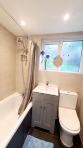 a bathroom with a toilet and a sink and a window at Woodside House - 4 Bed Town House - Central Reading - Free Parking in Reading