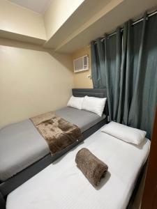 two beds in a small room with green curtains at Cozy 2 Bedroom Condo with Balcony for Rent in Iloilo City