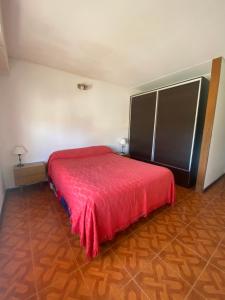 1 dormitorio con 1 cama con colcha roja en Chalet Mogotes en Mar del Plata