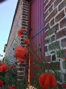 um edifício de tijolos com uma porta rosa e flores vermelhas em LE CLOS DE BEAUCHAMP APPARTEMENT Le BORD DE MER 2 vélos sont disponibles gratuitement em Saint-Valery-sur-Somme