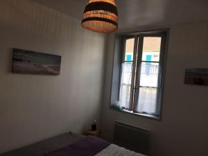 um quarto com uma cama, uma janela e um candeeiro em LE CLOS DE BEAUCHAMP APPARTEMENT Le BORD DE MER 2 vélos sont disponibles gratuitement em Saint-Valery-sur-Somme