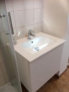 uma casa de banho branca com um lavatório e um chuveiro em LE CLOS DE BEAUCHAMP APPARTEMENT Le BORD DE MER 2 vélos sont disponibles gratuitement em Saint-Valery-sur-Somme