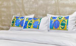 białe łóżko z 4 poduszkami na górze w obiekcie Hotel M'Rode w mieście Lomé