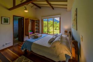 a bedroom with a large bed with a large window at Pousada Mandala das Águas in Aiuruoca