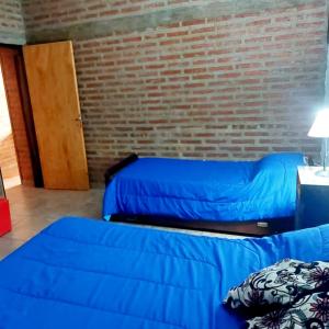 een kamer met 2 bedden en een bakstenen muur bij Cabaña Sarita in Santa Rosa