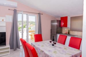 a kitchen and dining room with a table and red chairs at Villa Dreamer in Rogoznica