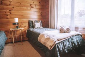 a bedroom with a bed with towels and a window at Comfortable Cosy Retreat in Rotorua