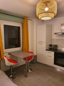 a kitchen with a table and two red chairs at CocooningSpace tout équipé + parking privé in Mulhouse