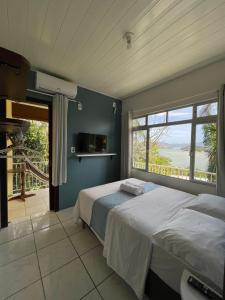 ein Schlafzimmer mit einem Bett und einem großen Fenster in der Unterkunft Moradas Dona Dalcema in Guarda do Embaú
