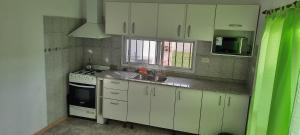 a kitchen with white cabinets and a sink and a stove at Casa Los Zorzales in San Pedro