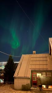 Cozy little house in Tromsø city في ترومسو: منزل بالشفق في السماء خلفه