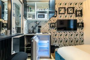 a small bedroom with a bed and a small refrigerator at Le Studio Du Parc Monceau in Paris