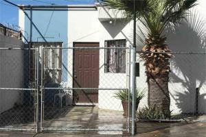 een hek met een palmboom voor een huis bij Casa Joyas in San Luis Río Colorado