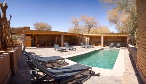 a swimming pool with lounge chairs next to a house at Lodge Quelana in San Pedro de Atacama