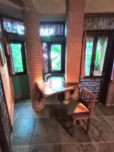 a wooden table and a chair in a room with windows at Posada Olivo in Mazunte