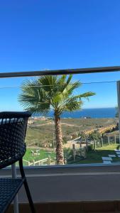 - une vue sur un palmier depuis la fenêtre dans l'établissement Beautiful new apartment with direct sea view, FIRST LINE!!, à Manilva