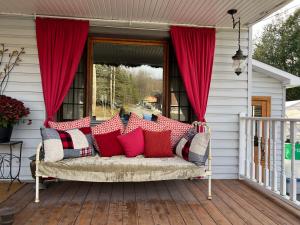 un sofá en un porche con cortinas rojas y una ventana en Auberge Old Chelsea, en Chelsea