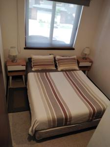 a bed in a room with two night stands and a window at Parque Pinares-Maravilloso-Playa -Muelle-Bosque in Pucón