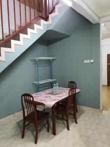 a dining room table with two chairs and a staircase at Homestay DeUmmah House in Cukai