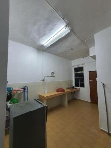 a room with a kitchen with a table and a refrigerator at Homestay DeUmmah House in Cukai
