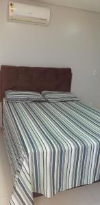 a bed with a striped comforter in a bedroom at Maravilhoso Apt 109 Home Service próximo Shopping Partage e Rodoviária in Campina Grande