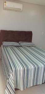 a bed with a striped comforter in a bedroom at Maravilhoso Apt 109 Home Service próximo Shopping Partage e Rodoviária in Campina Grande