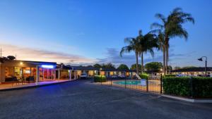 a building with a fence and palm trees at night at James Street Motor Inn in Toowoomba