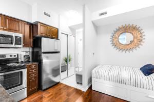 een keuken met een roestvrijstalen koelkast en een bed bij AOC Suites - High-Rise Condo - City View in Toronto
