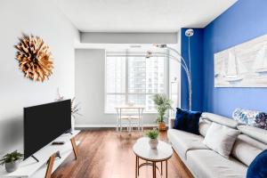 een woonkamer met een bank en een tv bij AOC Suites - High-Rise Condo - City View in Toronto