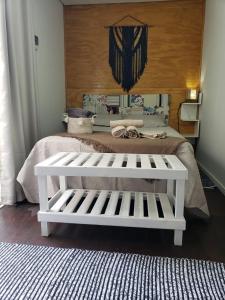 a white bench sitting in front of a bed at Moã do Mar Suítes in Guarda do Embaú