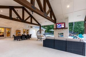 un patio interior con mesas, sillas y TV en 2 King Suites with Private Pool and Spa, Texas-Sized Covered Patio and Outdoor Kitchen and BBQ, en Tomball
