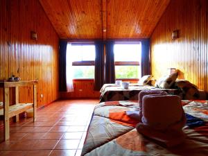 1 dormitorio con 2 camas y 2 ventanas en Miztli Lodge & Adventure, en Monteverde