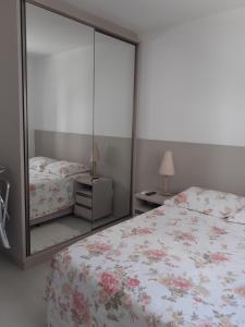 1 dormitorio con cama y espejo grande en Apartamento Encantador 250 metros do mar!, en Florianópolis