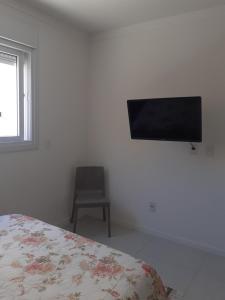 1 dormitorio con 1 cama y TV en la pared en Apartamento Encantador 250 metros do mar!, en Florianópolis