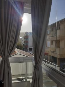 2 cortinas en una ventana con vistas a un edificio en Apartamento Encantador 250 metros do mar!, en Florianópolis