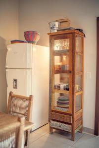 a cabinet with plates in it next to a refrigerator at Suítes Novas no Coração de Bonito in Bonito