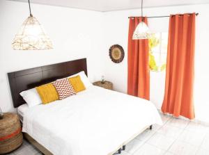 a bedroom with a bed with orange curtains and a window at Habitacion Fuego - Villa Valle Campo 
