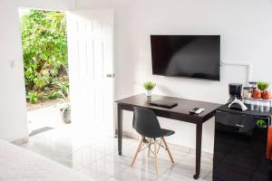 a desk with a chair and a television on a wall at Habitacion Fuego - Villa Valle Campo 