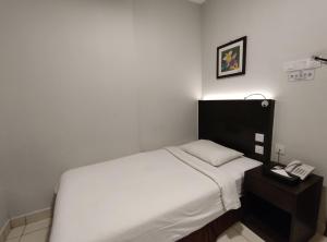 a bedroom with a white bed and a telephone at Hotel Desaru Penawar in Desaru