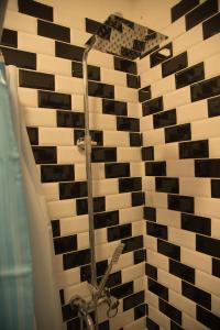y baño con ducha y azulejos blancos y negros. en La casita vieja en Perito Moreno