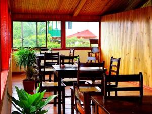 un comedor con mesas, sillas y ventanas en Miztli Lodge & Adventure, en Monteverde