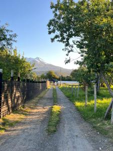 a dirt road with a fence and a mountain in the background at Cabañas Vista Volcanes I in Puerto Varas