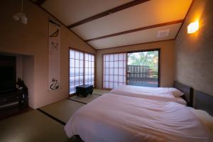 una camera da letto con un letto grande e una finestra di Innter Hill Tsubasa Yufuin a Yufu