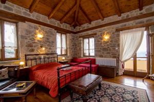 a bedroom with a red bed in a room with windows at Pigi Tarlampa Hotel in Ano Trikala