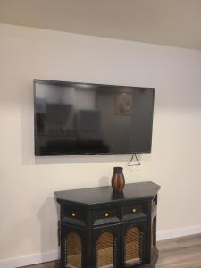 uma televisão de ecrã plano numa parede com uma mesa preta em Bethel Joyful Home em Winnipeg